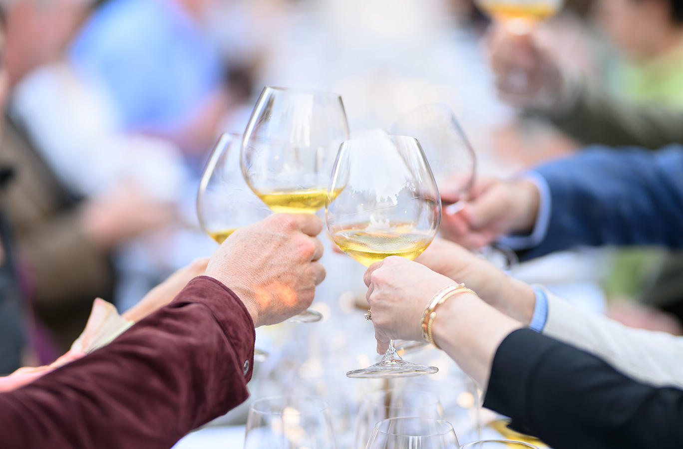 People cheering with wine glasses seated at a dinner table