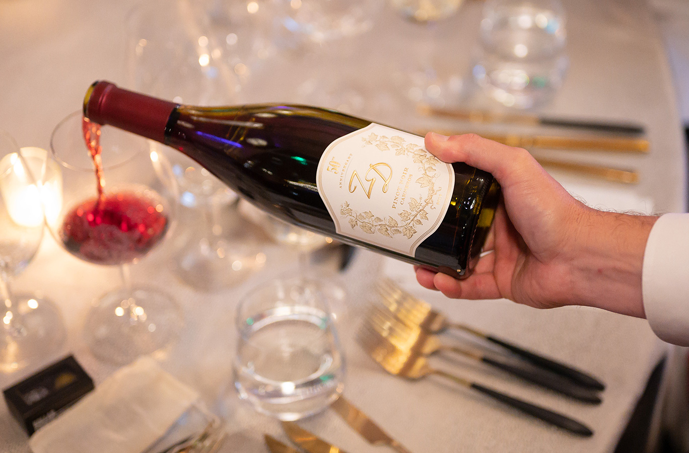 ZD Pinot Noir being poured into a wine glass on a dinner table