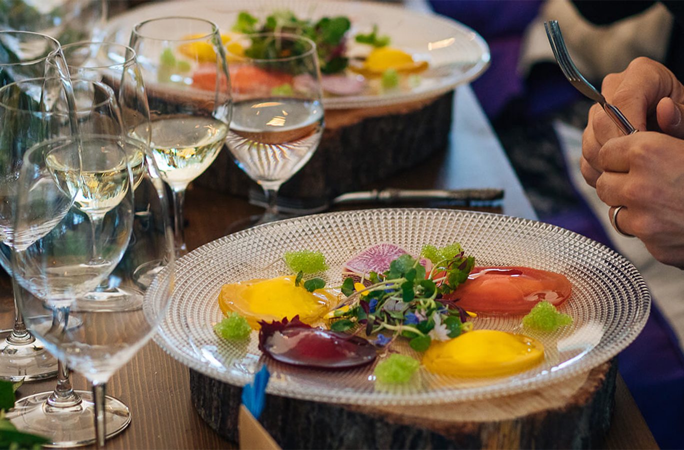 A colorful plate of food surrounded by wine glasses